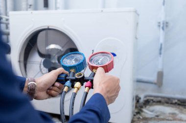 Teknisyen klimayı kontrol ediyor, klimaları doldurmak için ekipmanları ölçüyor..