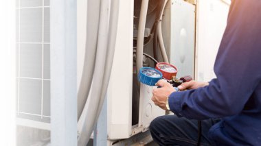 Teknisyen klimayı kontrol ediyor, klimaları doldurmak için ekipmanları ölçüyor..