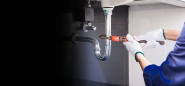 Tesisatçı ayarlanabilir anahtarla beyaz lavabo borusunu tamir ediyor..