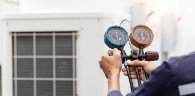 Teknisyen klimayı kontrol ediyor, klimaları doldurmak için ekipmanları ölçüyor..