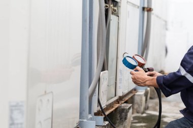 Teknisyen klimayı kontrol ediyor, klimaları doldurmak için ekipmanları ölçüyor..