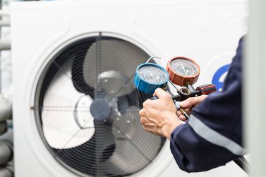 Teknisyen klimayı kontrol ediyor, klimaları doldurmak için ekipmanları ölçüyor..