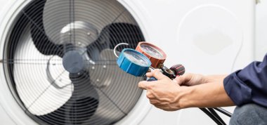 Teknisyen klimayı kontrol ediyor, klimaları doldurmak için ekipmanları ölçüyor..