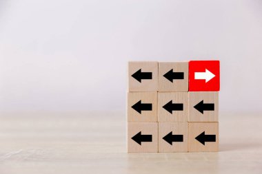 Siyah okların karşısında beyaz oklarla çevrili kırmızı tahta bloklar. Diğer insanlara göre farklı kavramlarla. Başarı için gidiyorum.