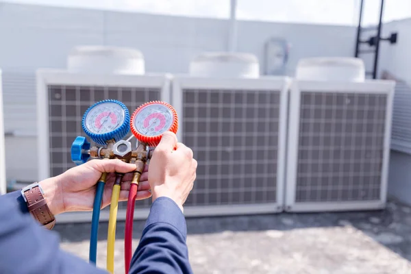 Teknisyen klimayı kontrol ediyor, klimaları doldurmak için ekipmanları ölçüyor..