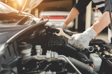 Otomobil tamircisi elleri ingiliz anahtarı, araba servisi ve bakımı ile bir araba motoru otomotiv atölyesini tamir ediyor..