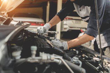 Otomobil tamircisi elleri ingiliz anahtarı, araba servisi ve bakımı ile bir araba motoru otomotiv atölyesini tamir ediyor..