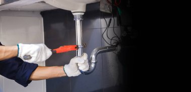 Tesisatçı ayarlanabilir anahtarla beyaz lavabo borusunu tamir ediyor..