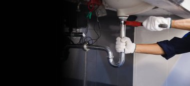 Tesisatçı ayarlanabilir anahtarla beyaz lavabo borusunu tamir ediyor..