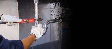 Tesisatçı ayarlanabilir anahtarla beyaz lavabo borusunu tamir ediyor..