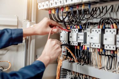 Elektrik mühendisi elektrik sistemi kontrol dolabındaki elektrik akımını ve elektrik hattını test etmek için çoklu metre kullanıyor..