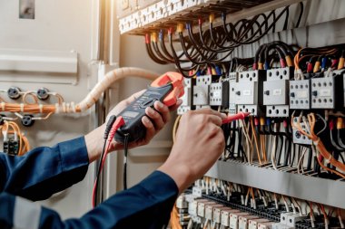 Elektrik mühendisi elektrik sistemi kontrol dolabındaki elektrik akımını ve elektrik hattını test etmek için çoklu metre kullanıyor..