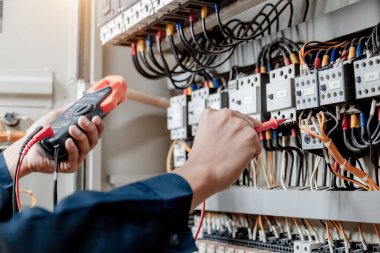 Elektrik mühendisi elektrik sistemi kontrol dolabındaki elektrik akımını ve elektrik hattını test etmek için çoklu metre kullanıyor..