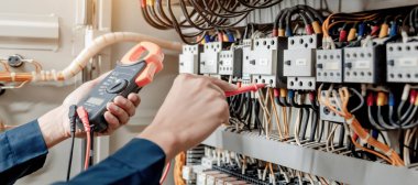 Elektrik mühendisi elektrik sistemi kontrol dolabındaki elektrik akımını ve elektrik hattını test etmek için çoklu metre kullanıyor..