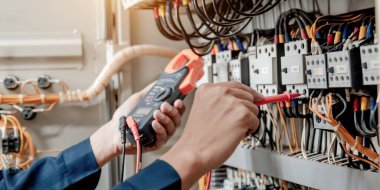 Elektrik mühendisi elektrik sistemi kontrol dolabındaki elektrik akımını ve elektrik hattını test etmek için çoklu metre kullanıyor..
