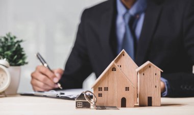 Buy or Rent 'le çalışan iş adamı, kopyalama alanı. Mülk yatırımı ve ev kredisi finansal konsepti El 'in ahşap eve para yığını koyması..