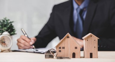 Buy or Rent 'le çalışan iş adamı, kopyalama alanı. Mülk yatırımı ve ev kredisi finansal konsepti El 'in ahşap eve para yığını koyması..