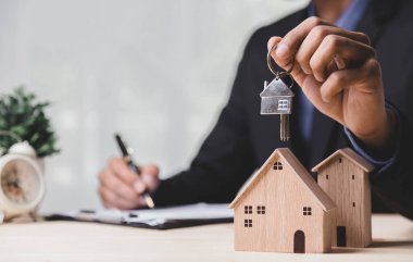 Buy or Rent 'le çalışan iş adamı, kopyalama alanı. Mülk yatırımı ve ev kredisi finansal konsepti El 'in ahşap eve para yığını koyması..