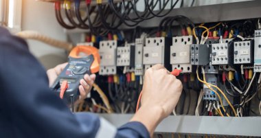 Elektrik mühendisi elektrik kabinesi kontrolündeki voltaj ve elektrik akımını ölçen bir testçi, elektrik sisteminin işleyişini konsept olarak kontrol ediyor .