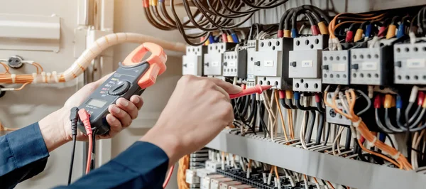 Elektrik mühendisi elektrik sistemi kontrol dolabındaki elektrik akımını ve elektrik hattını test etmek için çoklu metre kullanıyor..