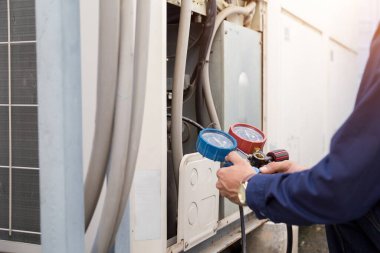 Teknisyen klimayı kontrol ediyor, klimaları doldurmak için ekipmanları ölçüyor..