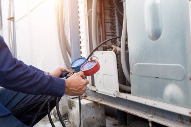 Teknisyen klimayı kontrol ediyor, klimaları doldurmak için ekipmanları ölçüyor..