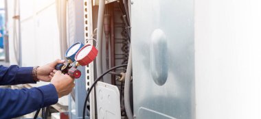 Teknisyen klimayı kontrol ediyor, klimaları doldurmak için ekipmanları ölçüyor..
