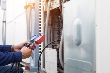 Teknisyen klimayı kontrol ediyor, klimaları doldurmak için ekipmanları ölçüyor..