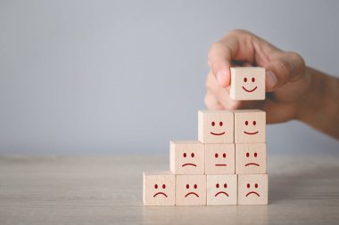 Customer pressing smiley face emoticon on wood cube, Service rating, satisfaction concept.