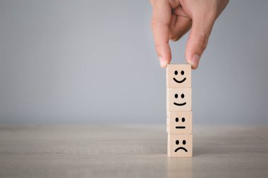 Customer pressing smiley face emoticon on wood cube, Service rating, satisfaction concept.