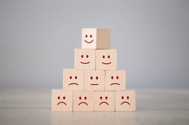 Customer pressing smiley face emoticon on wood cube, Service rating, satisfaction concept.