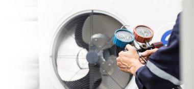 Teknisyen klimayı kontrol ediyor, klimaları doldurmak için ekipmanları ölçüyor..