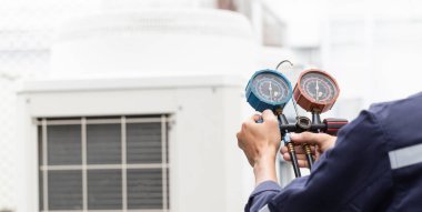 Teknisyen klimayı kontrol ediyor, klimaları doldurmak için ekipmanları ölçüyor..