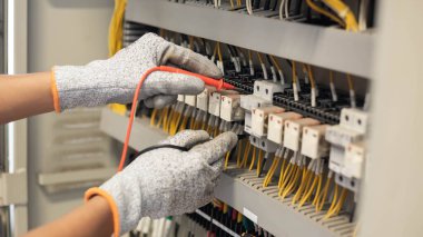 Elektrik mühendisi elektrik sistemi kontrol dolabındaki elektrik akımını ve elektrik hattını test etmek için çoklu metre kullanıyor..