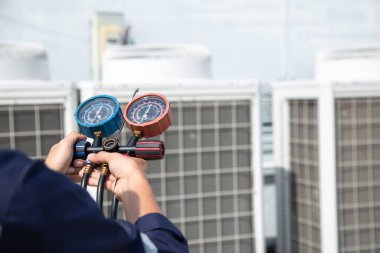Teknisyen klimayı kontrol ediyor, klimaları, servis ve bakım klimalarını doldurmak için ölçüm aletleri kullanıyor. .