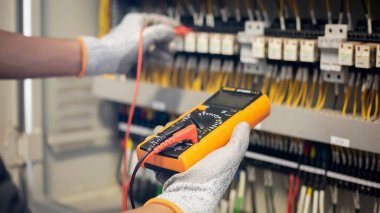 Elektrik mühendisi elektrik sistemi kontrol dolabındaki elektrik akımını ve elektrik hattını test etmek için çoklu metre kullanıyor..