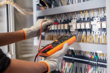 Elektrik mühendisi elektrik sistemi kontrol dolabındaki elektrik akımını ve elektrik hattını test etmek için çoklu metre kullanıyor..