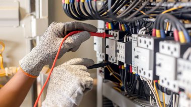 Elektrik mühendisi elektrik sistemi kontrol dolabındaki elektrik akımını ve elektrik hattını test etmek için çoklu metre kullanıyor..