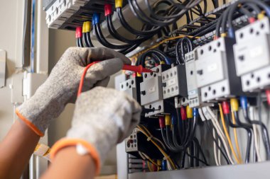 Elektrik mühendisi elektrik sistemi kontrol dolabındaki elektrik akımını ve elektrik hattını test etmek için çoklu metre kullanıyor..