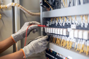 Elektrik mühendisi elektrik sistemi kontrol dolabındaki elektrik akımını ve elektrik hattını test etmek için çoklu metre kullanıyor..