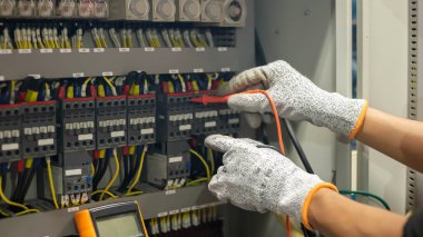 Elektrik mühendisi elektrik sistemi kontrol dolabındaki elektrik akımını ve elektrik hattını test etmek için çoklu metre kullanıyor..