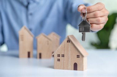 Buy or Rent 'le çalışan iş adamı, kopyalama alanı. Mülk yatırımı ve ev kredisi finansal konsepti El 'in ahşap eve para yığını koyması..