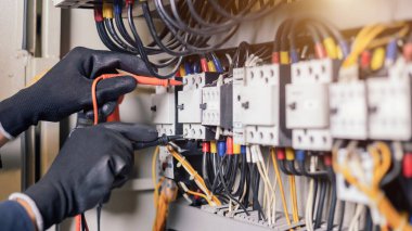 Elektrik mühendisi, elektrik kabinesi kontrolündeki voltaj ve elektrik akımını ölçen bir testçi ve röle koruma sistemindeki kabloları kontrol ediyor. Körfez kontrol birimi. Orta gerilim şalteri.