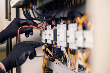 Elektrik mühendisi, elektrik kabinesi kontrolündeki voltaj ve elektrik akımını ölçen bir testçi ve röle koruma sistemindeki kabloları kontrol ediyor. Körfez kontrol birimi. Orta gerilim şalteri.