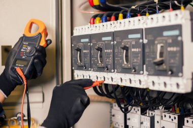 Elektrik mühendisi, elektrik kabinesi kontrolündeki voltaj ve elektrik akımını ölçen bir testçi ve röle koruma sistemindeki kabloları kontrol ediyor. Körfez kontrol birimi. Orta gerilim şalteri.
