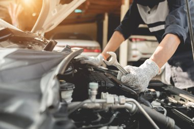 Otomobil tamircisi elleri ingiliz anahtarı, araba servisi ve bakımı ile bir araba motoru otomotiv atölyesini tamir ediyor..