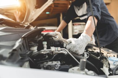 Otomobil tamircisi elleri ingiliz anahtarı, araba servisi ve bakımı ile bir araba motoru otomotiv atölyesini tamir ediyor..