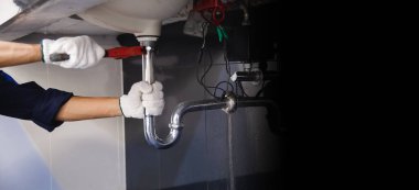 Tesisatçı ayarlanabilir anahtarla beyaz lavabo borusunu tamir ediyor..