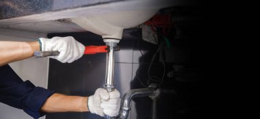 Tesisatçı ayarlanabilir anahtarla beyaz lavabo borusunu tamir ediyor..