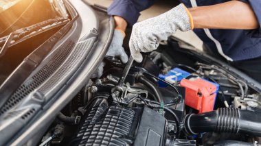 Otomobil tamircisi elleri ingiliz anahtarı, araba servisi ve bakımı ile bir araba motoru otomotiv atölyesini tamir ediyor..